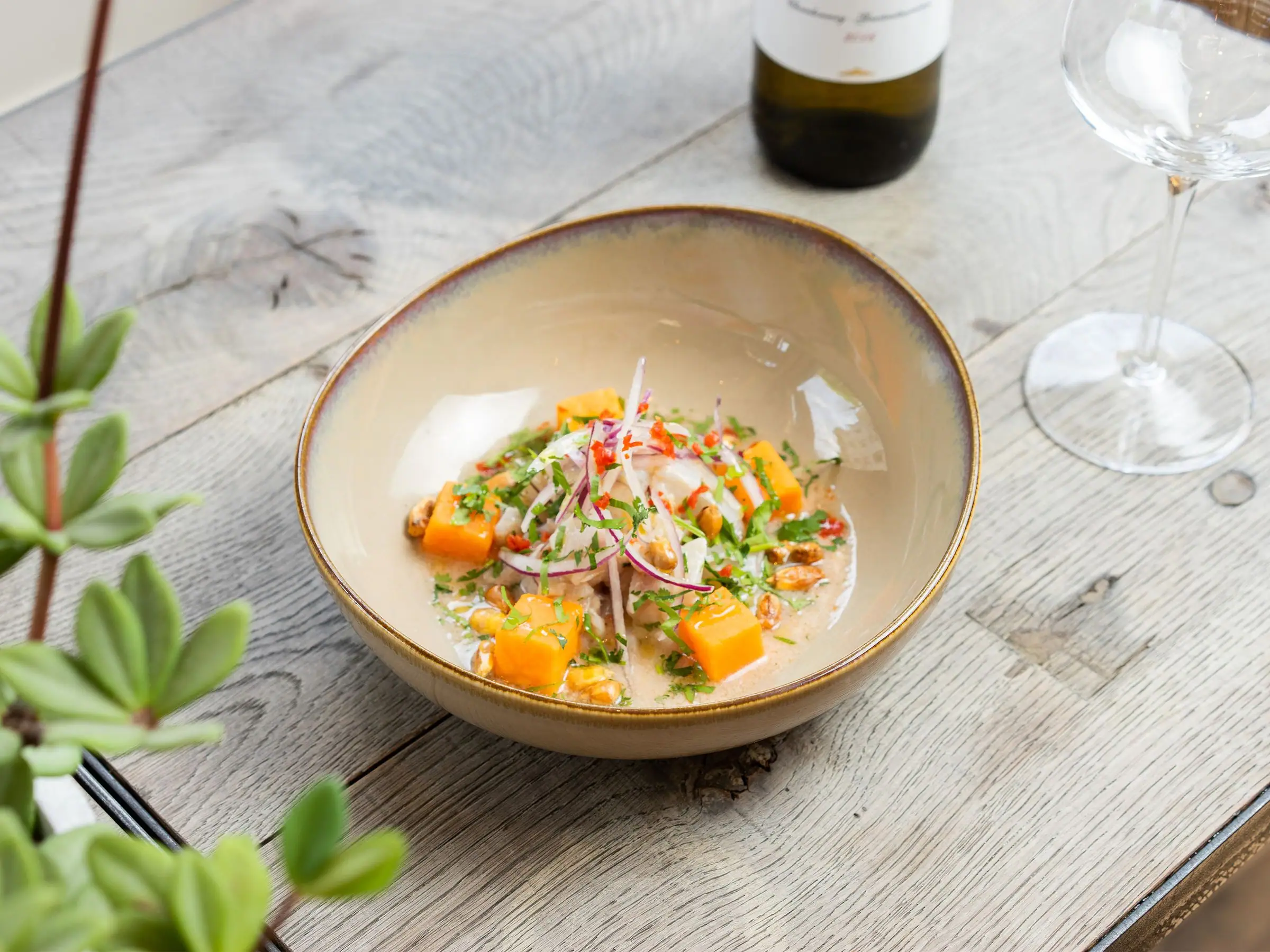 Peruvian sea bream ceviche with sweet potato, onion and corn in a ceramic bowl.