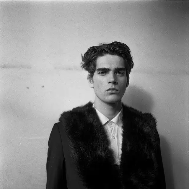 Black-and-white portrait of a man in a white shirt and dark fur-collar coat.